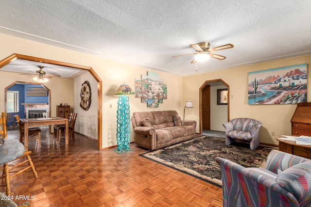 living room featuring a textured ceiling, parquet floors, and ceiling fan