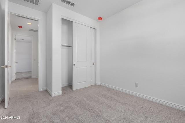 unfurnished bedroom with light colored carpet and a closet