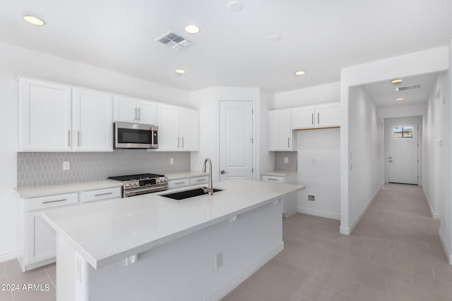 kitchen with stainless steel appliances, white cabinetry, a center island with sink, and sink