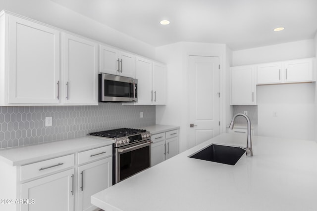 kitchen with white cabinets, decorative backsplash, sink, and appliances with stainless steel finishes