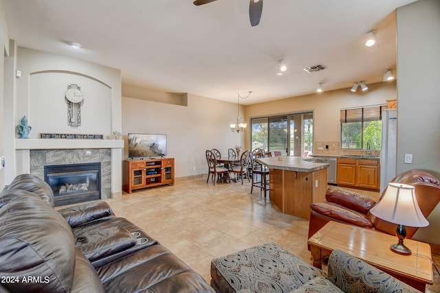 tiled living room featuring a tile fireplace, ceiling fan with notable chandelier, and sink