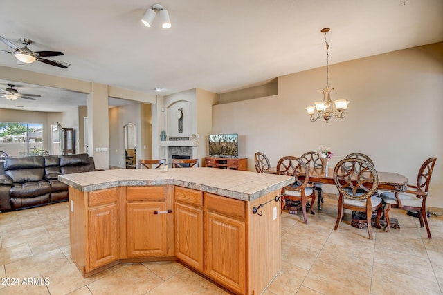 kitchen with a center island, ceiling fan with notable chandelier, decorative light fixtures, and light tile patterned floors