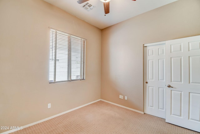 unfurnished bedroom featuring ceiling fan, light carpet, and a closet