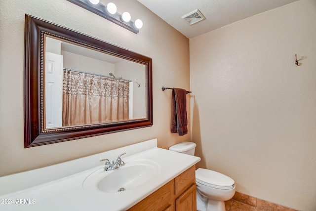 bathroom featuring tile patterned flooring, a textured ceiling, vanity, and toilet