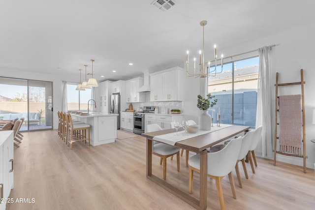 dining area with an inviting chandelier, light hardwood / wood-style floors, and a healthy amount of sunlight