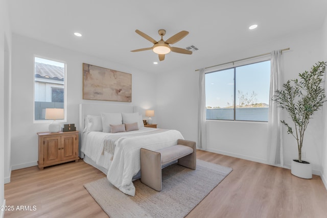 bedroom with light hardwood / wood-style floors, ceiling fan, and a water view