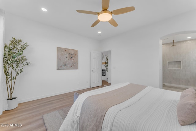 bedroom with ceiling fan, ensuite bathroom, and light wood-type flooring