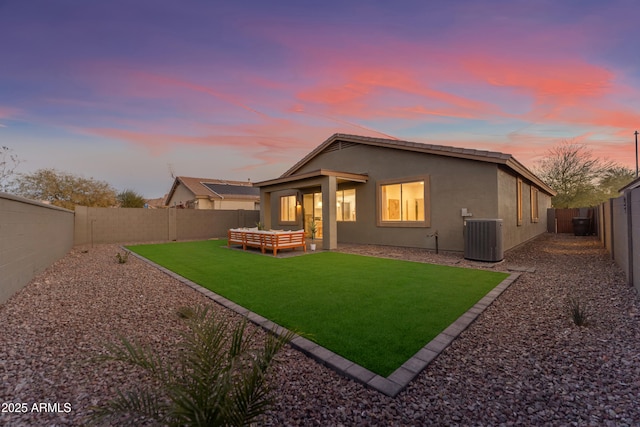 back house at dusk featuring cooling unit, an outdoor living space, and a yard