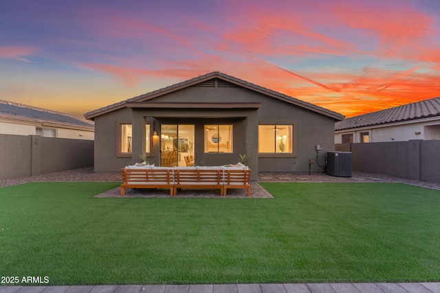 back house at dusk with an outdoor living space, central AC unit, a patio area, and a yard