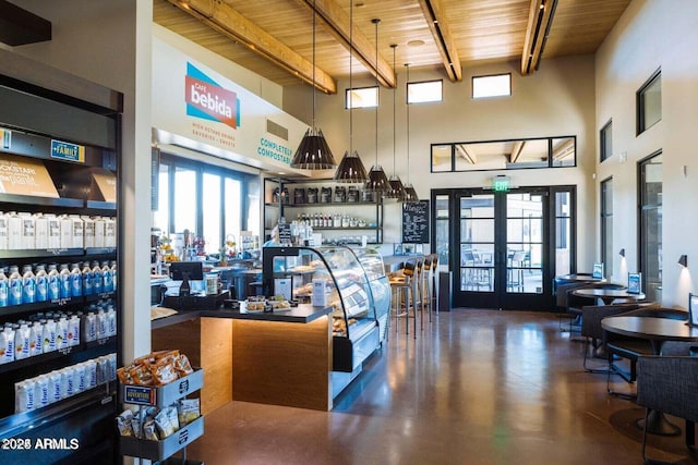 interior space with a towering ceiling, bar, wood ceiling, and french doors