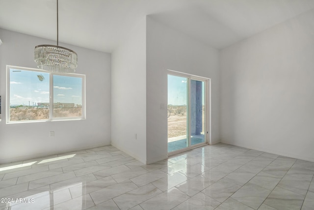 unfurnished room with a notable chandelier, light tile patterned flooring, and a wealth of natural light