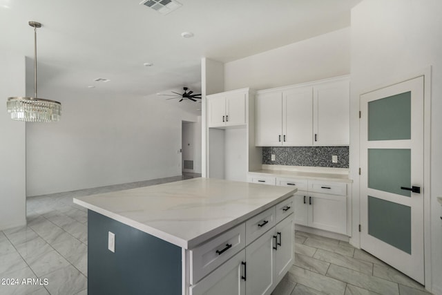 kitchen featuring hanging light fixtures, white cabinets, ceiling fan, backsplash, and light tile patterned flooring