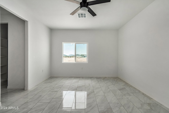 tiled empty room featuring ceiling fan