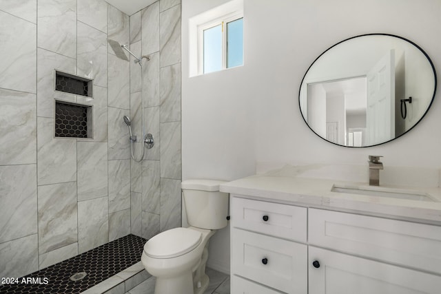 bathroom with vanity, toilet, and tiled shower