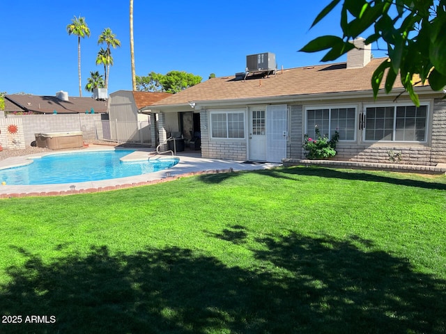 rear view of house featuring cooling unit, a yard, a patio, a hot tub, and a storage unit