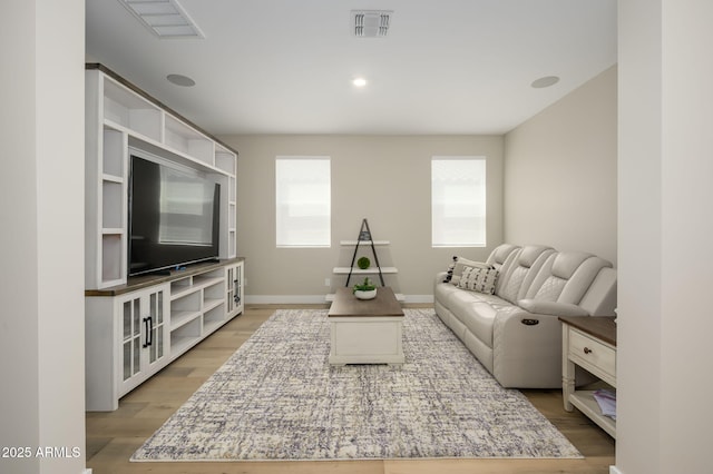 living room featuring baseboards, visible vents, and wood finished floors