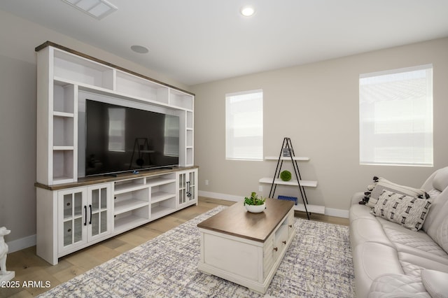 living area featuring baseboards, light wood finished floors, and visible vents