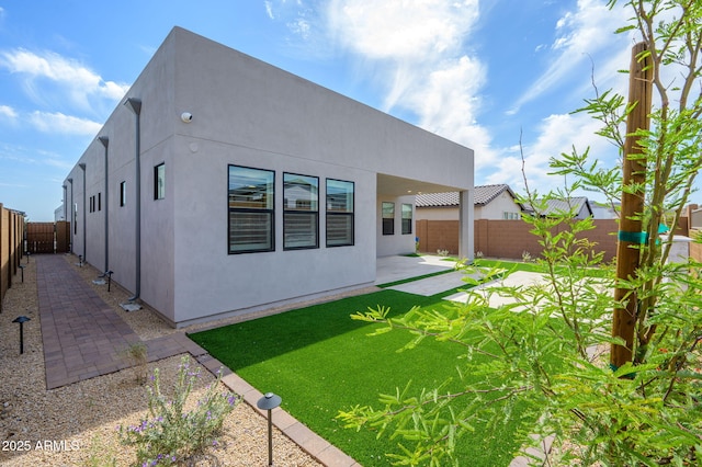rear view of property featuring a lawn, a fenced backyard, a patio area, and stucco siding