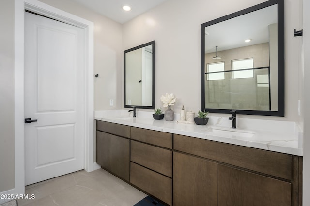 full bath with a sink, double vanity, and tiled shower