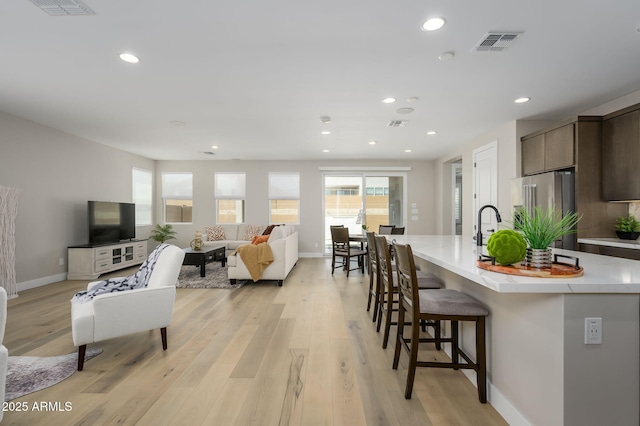 living area featuring light wood-style floors, baseboards, recessed lighting, and visible vents
