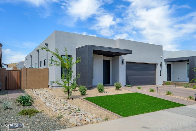 modern home featuring a gate, an attached garage, driveway, and stucco siding