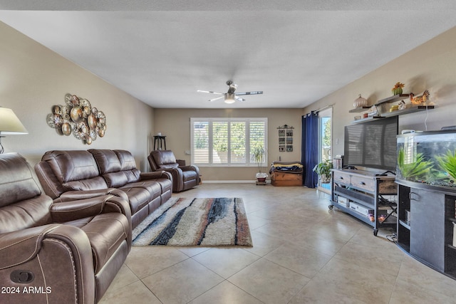 living room featuring ceiling fan, light tile patterned flooring, and a textured ceiling