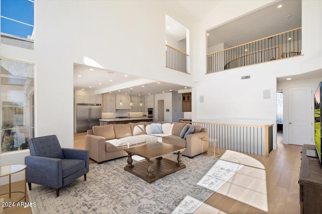 living room featuring a towering ceiling and light hardwood / wood-style flooring