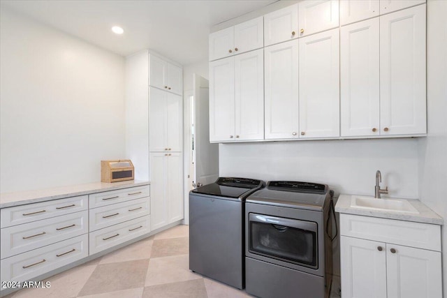 clothes washing area featuring washing machine and dryer, sink, and cabinets