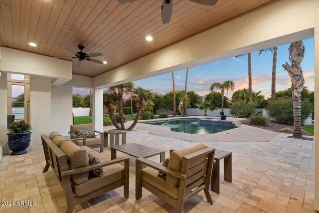 pool at dusk featuring outdoor lounge area, a patio, and ceiling fan