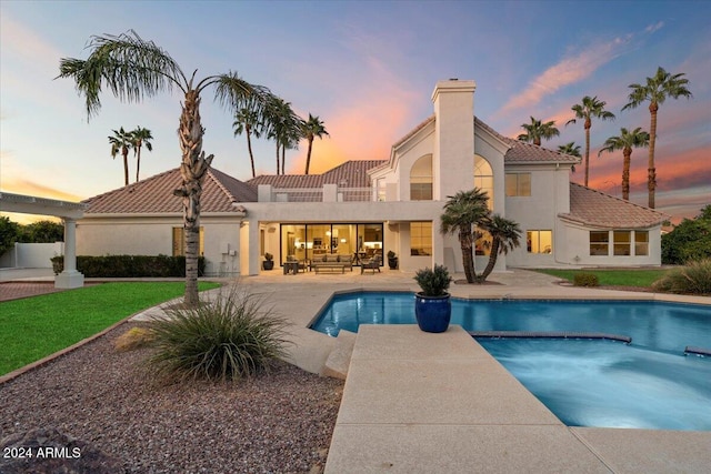 pool at dusk featuring a patio area and a yard