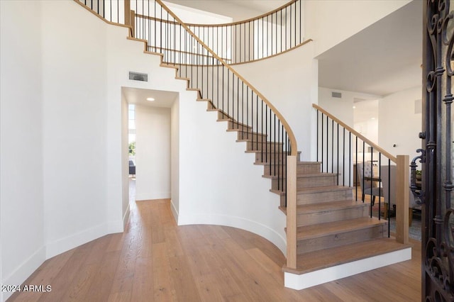 stairs featuring a towering ceiling and hardwood / wood-style flooring