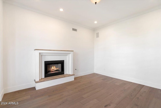 unfurnished living room featuring wood-type flooring and ornamental molding