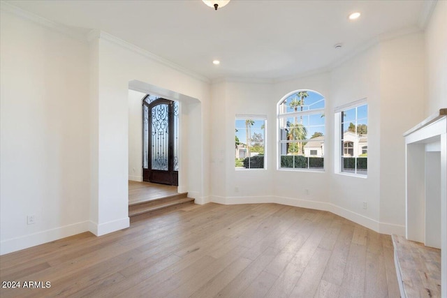 unfurnished living room with ornamental molding and light hardwood / wood-style floors