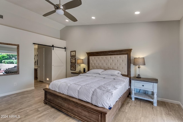 bedroom featuring ceiling fan, light hardwood / wood-style floors, lofted ceiling, and a barn door