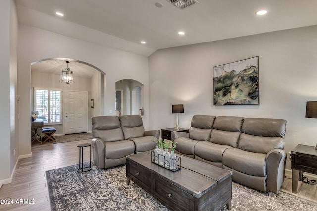 living room featuring hardwood / wood-style flooring, lofted ceiling, and a chandelier