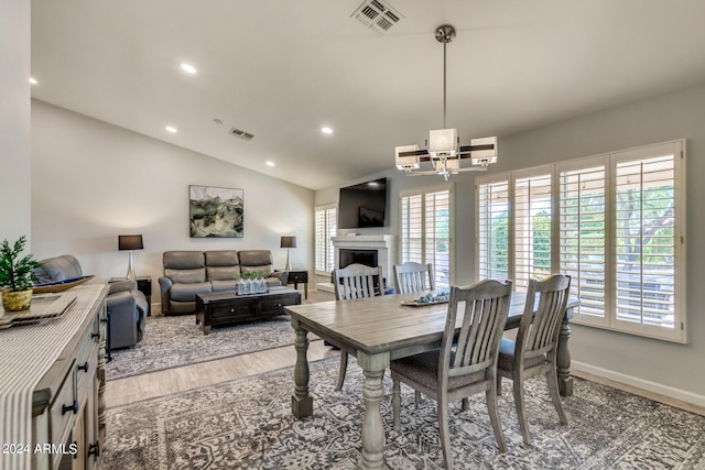 dining space with a notable chandelier, light hardwood / wood-style floors, vaulted ceiling, and a wealth of natural light