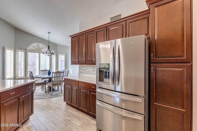 kitchen with a chandelier, hanging light fixtures, vaulted ceiling, backsplash, and stainless steel fridge with ice dispenser