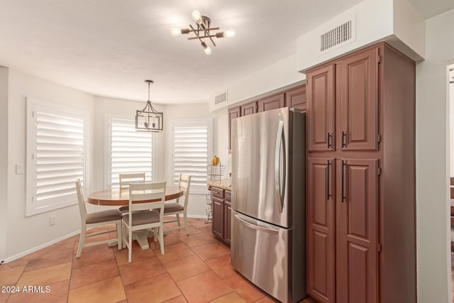 kitchen with light stone countertops, stainless steel fridge, pendant lighting, a chandelier, and light tile patterned flooring