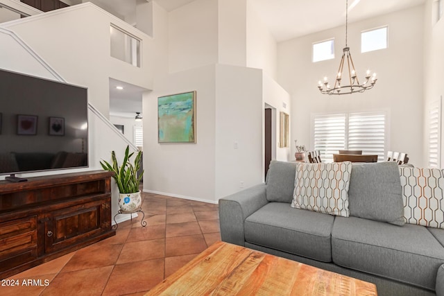 tiled living room with ceiling fan with notable chandelier and a high ceiling