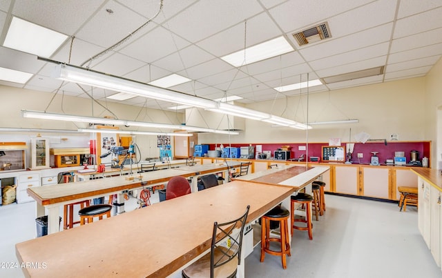 miscellaneous room with a workshop area, concrete flooring, and a paneled ceiling