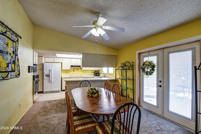 dining space with a healthy amount of sunlight, vaulted ceiling, light carpet, and ceiling fan