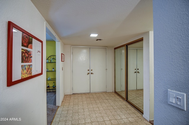 hallway featuring a textured ceiling and light tile flooring