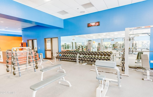 exercise room featuring a high ceiling, ceiling fan, and a drop ceiling