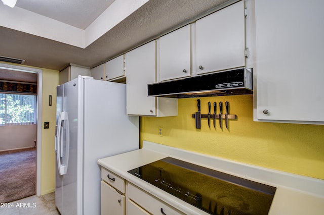 kitchen with white refrigerator, white cabinetry, and light tile floors