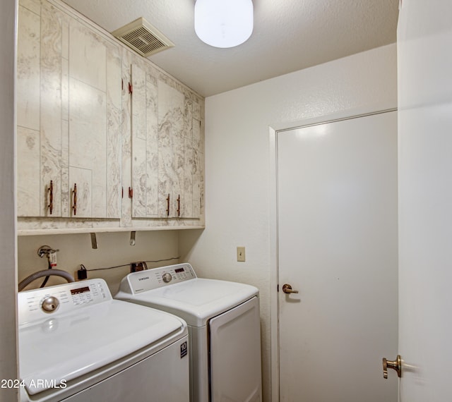 laundry area with cabinets, a textured ceiling, washing machine and dryer, and washer hookup