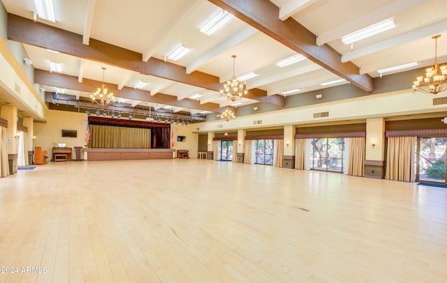 interior space with a notable chandelier, beam ceiling, a healthy amount of sunlight, and hardwood / wood-style floors