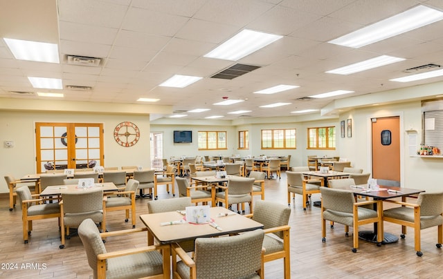 dining space featuring light hardwood / wood-style flooring, french doors, and a drop ceiling