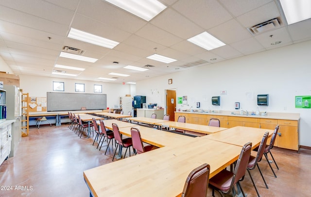 dining area with concrete floors and a paneled ceiling