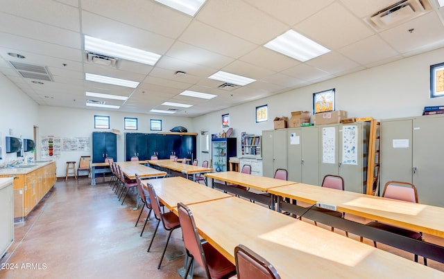 dining space featuring concrete flooring and a drop ceiling