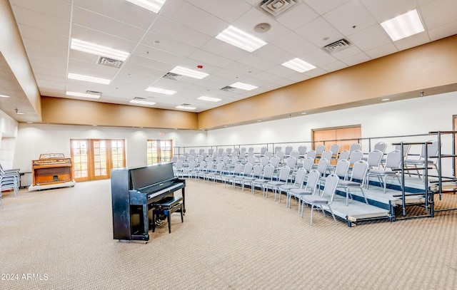 exercise room featuring a towering ceiling, french doors, carpet flooring, and a drop ceiling